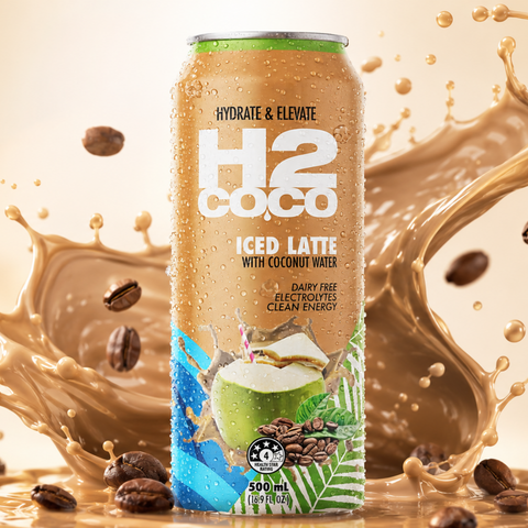 A 500ml can of H2coco Iced Latte with coconut milk, set against a dynamic backdrop of a milk splash and scattered coffee beans on a warm beige background.